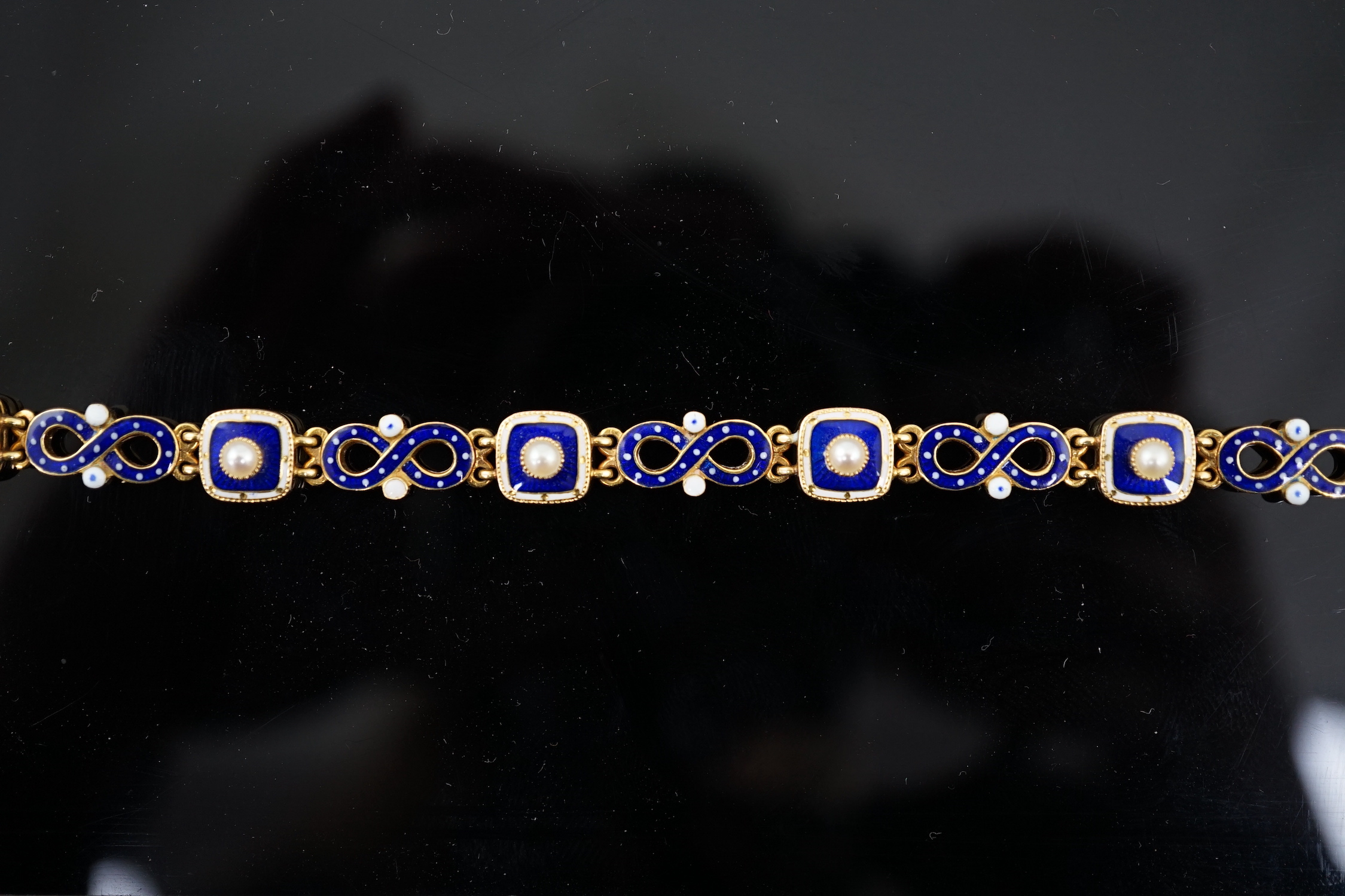 An early 20th century gold (tests as 18ct), two colour enamel and spilt pearl set bracelet